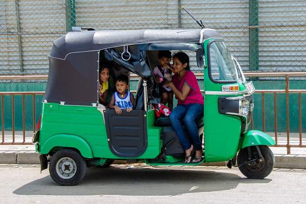 Image d’un tuk tuk indien avec une famille dedans pour illustrer l’article sur l’achat de voitures destinées aux familles nombreuses.