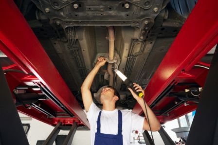 mechanic standing under car engine and holding lamp. Copy space